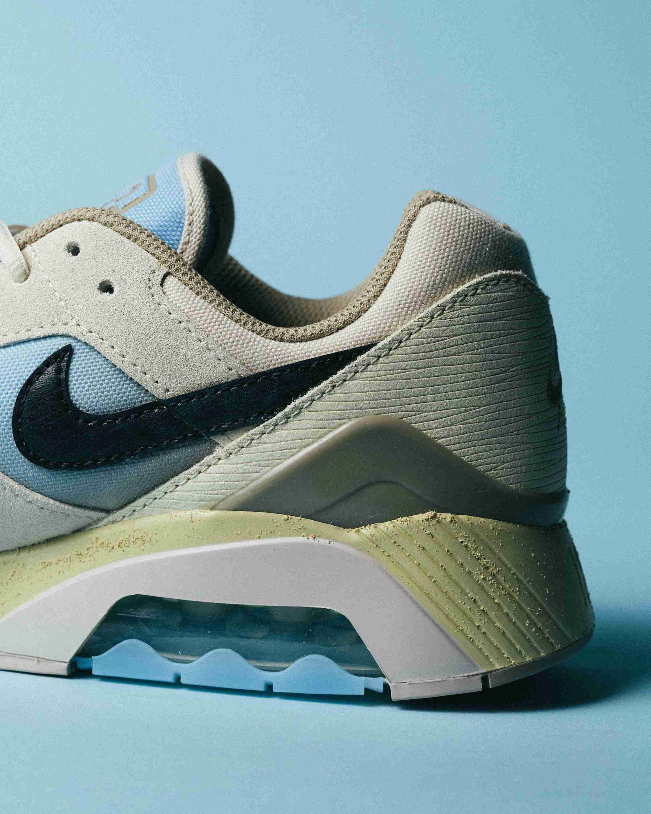 Paire de sneakers beige et bleu clair posée sur un fond bleu, vue de trois quarts avec mise en avant des formes et détails du modèle.